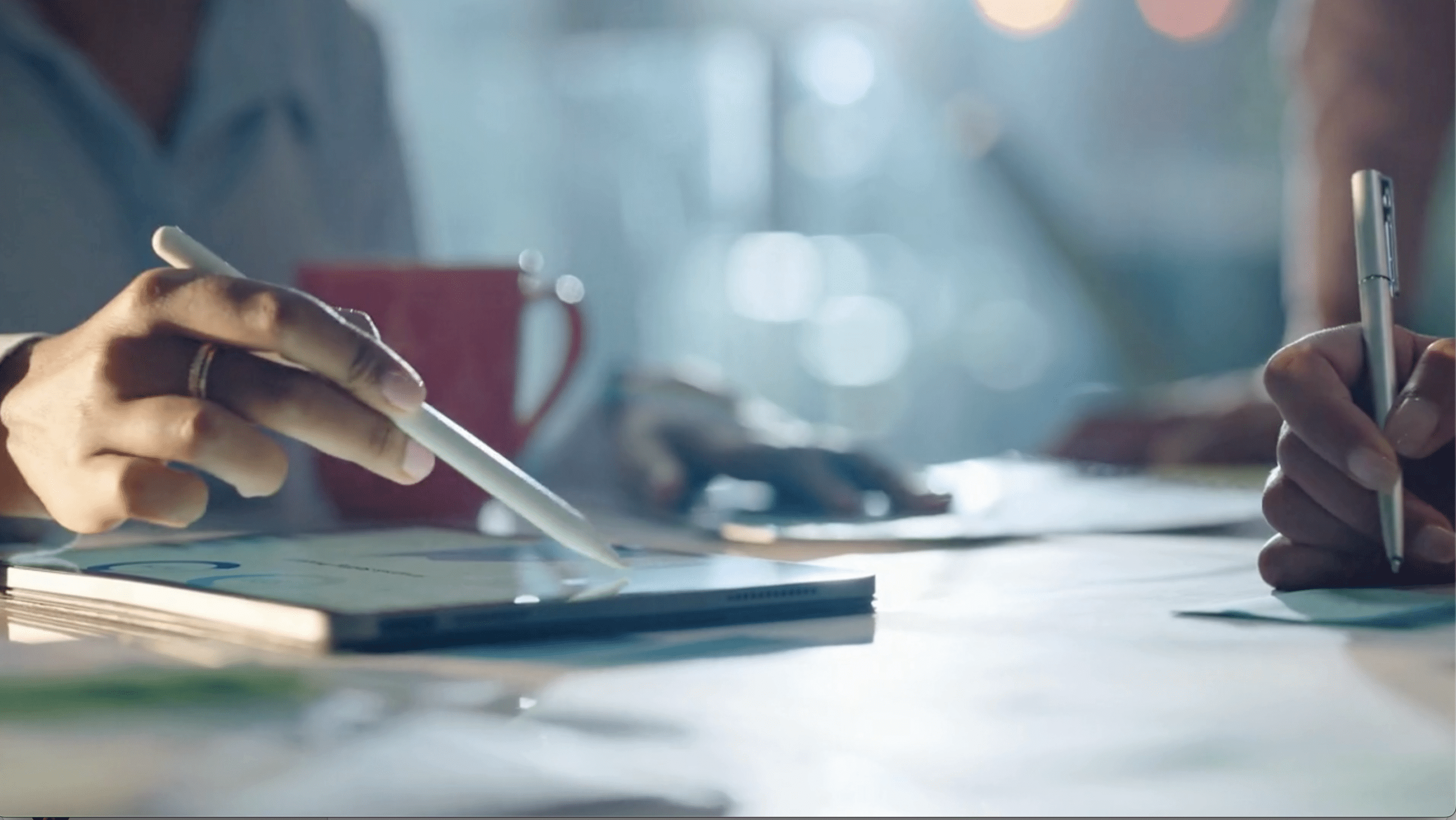 Two people collaborating at a desk, reviewing documents over an ipad